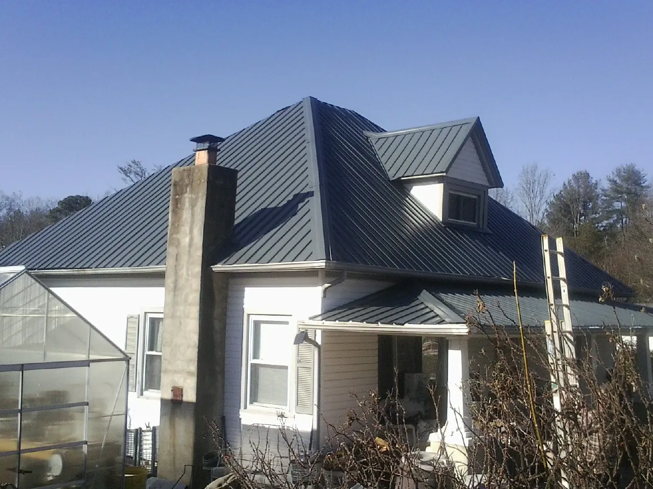 Dark blue standing seam metal roof on a white farmhouse with dormer — Slate & Tile Roof Repair by Roofing Brothers in White Mills
