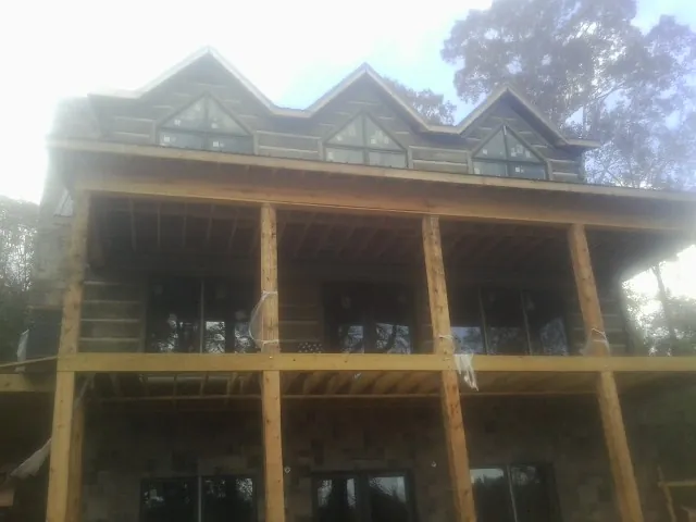 Dormers and porch framing on a large log home under construction — Roof Coating work by our crew in White Mills