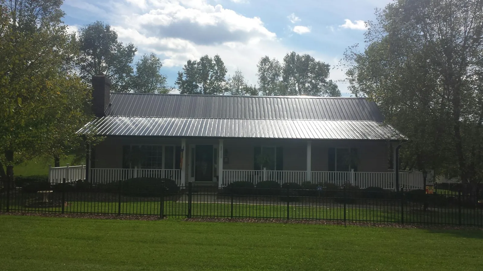 Gray metal roof on a brick ranch with a full width front porch — Gutter Guard Installation work by our crew in White Mills
