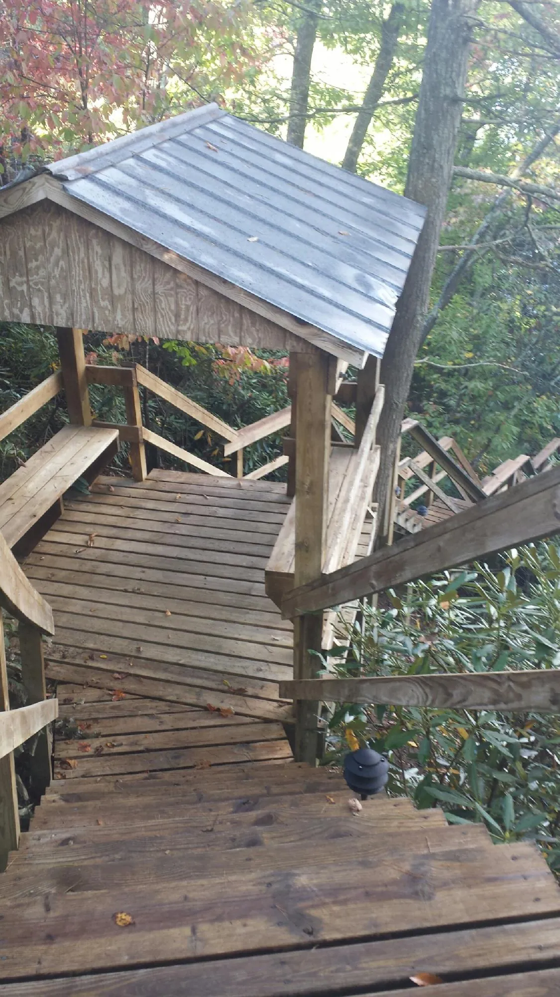 Metal roofed shelter over wooden steps on a wooded walkway — Skylight Repair & Installation work by our crew in White Mills