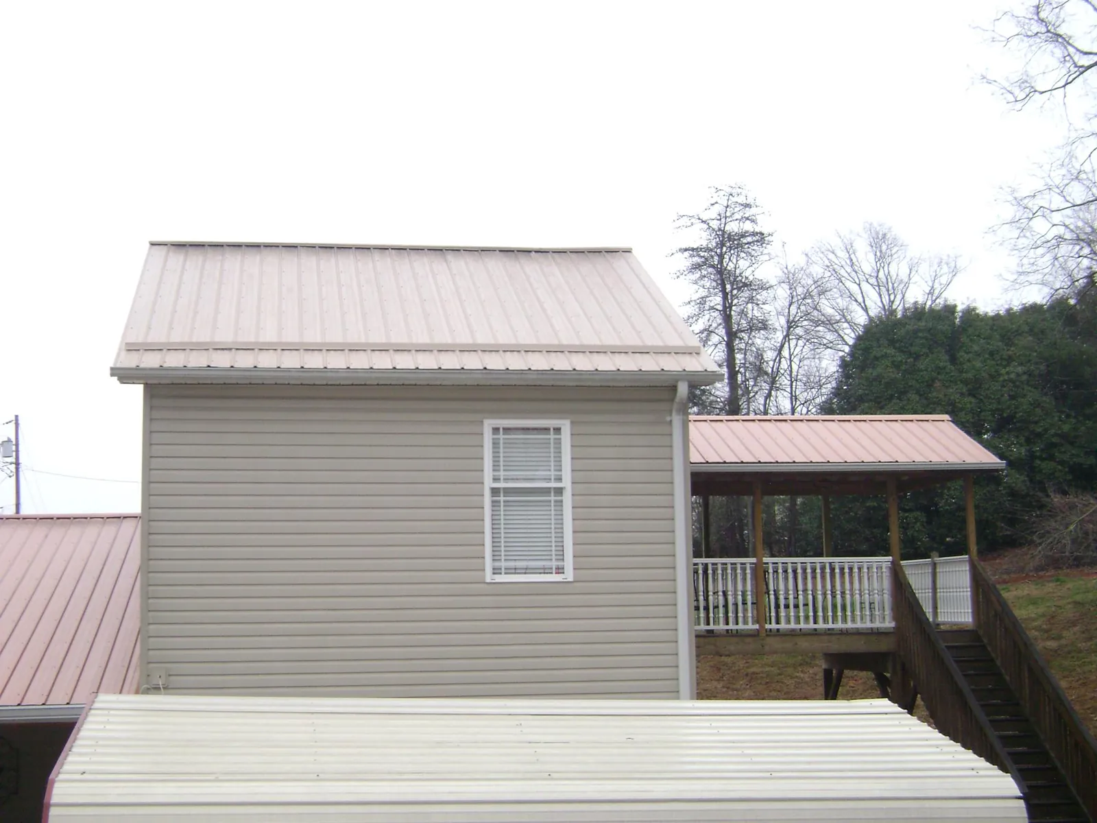 Tan metal roofs on a two story addition and attached porch, from a Roof Replacement job in White Mills