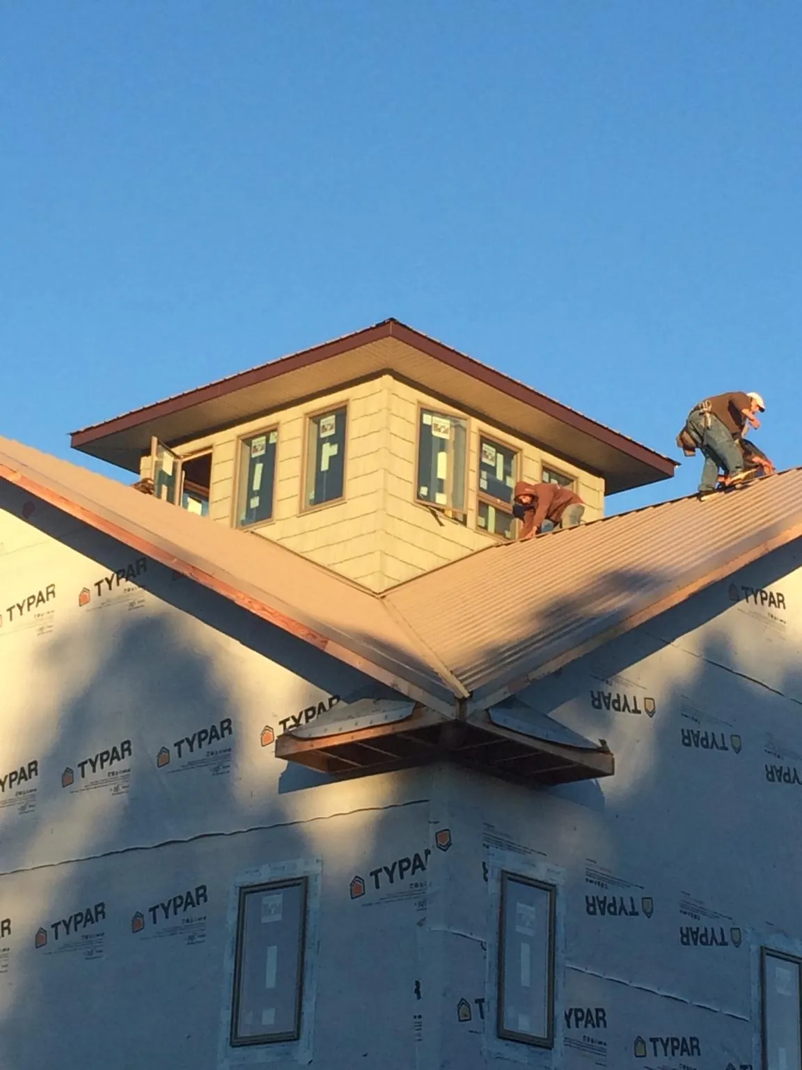 Roofers working around a rooftop cupola on a new metal roof at sunset — Roof Waterproofing in White Mills by Roofing Brothers
